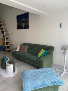 ein Wohnzimmer mit einer grünen Couch und einer Treppe in der Unterkunft Cap d'Agde Naturiste Hélio-village 95 in Cap d'Agde