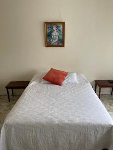 a white bed with a red pillow on top of it at Lovely apartment in the heart of Tangier in Tangier