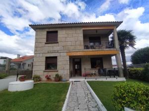 une maison avec un balcon et une cour dans l'établissement Apartamento en SANXENXO Planta alta, à Sanxenxo