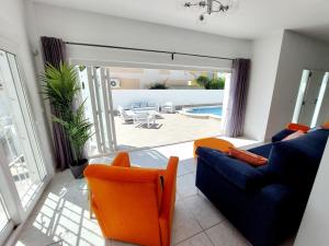 salon z niebieską kanapą i pomarańczowymi krzesłami w obiekcie Villa Palma - Heated Pool w mieście Los Alcázares