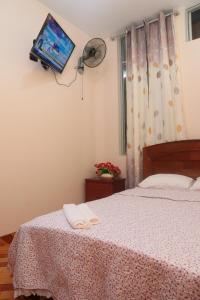 1 dormitorio con 1 cama y TV en la pared en Flor del Valle, en Tarapoto