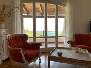 a living room with two chairs and a table and a large window at Casa Le Cicale in Porto Istana