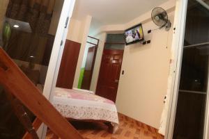 um pequeno quarto com uma cama e uma televisão na parede em Flor del Valle em Tarapoto