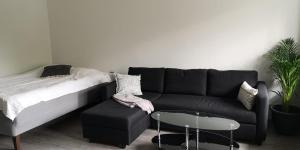ein Wohnzimmer mit einem schwarzen Sofa und einem Tisch in der Unterkunft Cosy studio near by AirPort, 2min from train! in Vantaa