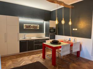 チヴィダーレ・デル・フリウーリにあるB&B Dai Toscansのキッチン(赤いテーブル、白い椅子付)