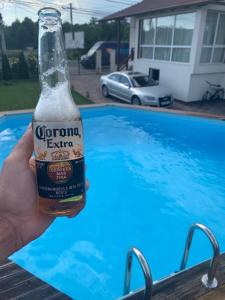 a person holding a bottle of beer next to a swimming pool at Casa Deac in Sebeş