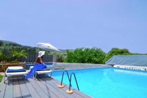 a woman sitting on a chair next to a swimming pool at Villa Olive Tree with Private Pool in Kissamos