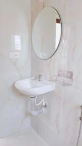 een witte badkamer met een wastafel en een spiegel bij Villa de Montana in Kodaikānāl