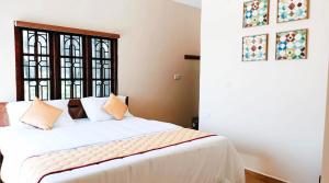 een slaapkamer met een wit bed met kussens en een raam bij Villa de Montana in Kodaikānāl