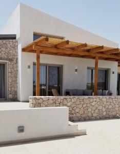 Casa blanca con pared de piedra y pérgola de madera en Alykes Beachside Stylish Villas with Private Pool South Rhodes en Lakhaniá