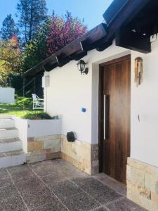 Casa blanca con puerta de madera y escaleras en La Tante en San Carlos de Bariloche
