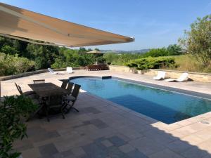 a swimming pool with a table and an umbrella at L'adret du bois in Sames