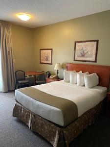 una habitación de hotel con una cama grande y una mesa en Village Creek Country Inn, en Westerose
