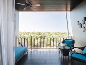 a room with a balcony with a couch and chairs at Avani Plus Mai Khao Phuket Suites in Mai Khao Beach
