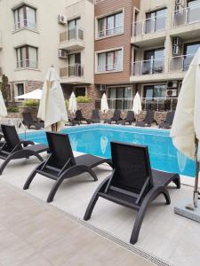 a row of chairs and umbrellas next to a swimming pool at Апартамент Весела-Хоризонт in Sozopol