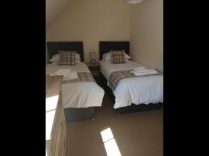two beds in a room with sunlight shining on them at No4 Millhouse Flats in Inverlochy