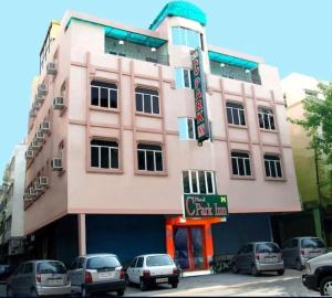 a pink building with cars parked in front of it at The C Park Inn Karol Bagh Homely Atmosphere in New Delhi