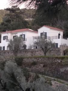 a white house on top of a stone wall at Eri Rooms to Let in Raches