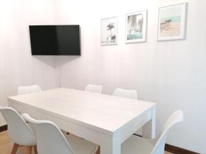 a white table with white chairs and a tv on a wall at Trajadinha B in Caminha in Caminha