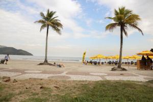 サントスにあるSANTOS - TURISMO E HOME OFFICEの2本のヤシの木とビーチパラソルを持った人々