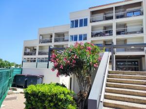 an apartment building with stairs and flowers in front of it at Studio centre port,piscine et parking sous terrain in Cap d'Agde
