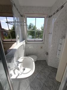 a white bathroom with a sink and a window at Apartamenty Hexagon nr 32 in Grzybowo