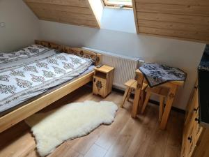 ein Schlafzimmer mit einem Bett, einem Hocker und einem weißen Teppich in der Unterkunft Apartamenty w cichej okolicy in Bańska Wyżna