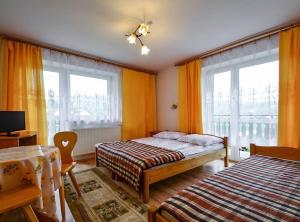 een slaapkamer met 2 bedden en 2 ramen bij Pokoje gościnne u Bożenki in Krościenko