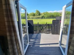 an open door to a deck with a view of a field at Caledonian Pod. In Caol, Fort William in Caol