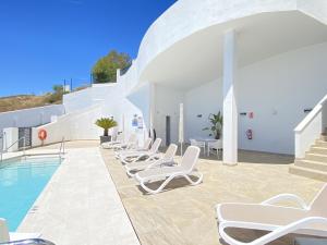 a pool with lounge chairs next to a building at Terrazas de Ladera V5 Casasol in Nerja