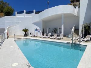 a large swimming pool with chairs and a building at Terrazas de Ladera V5 Casasol in Nerja