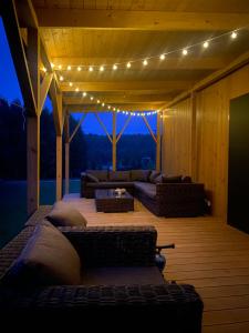 - un salon avec un canapé et des lumières sur la terrasse dans l'établissement Baciki 61- domek przy lesie, à Baciki Dalsze