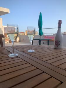 カリアリにあるNuovo attico con terrazza 5 minuti dal mareの木製テーブルに座るワイングラス3杯(ボトル付)