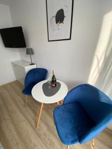a room with two blue chairs and a table with a bottle of wine at Dom gościnny Jarek in Rowy