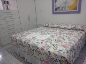 1 dormitorio con 1 cama con colcha de flores en Flat na Praia do Farol da Barra, en Salvador