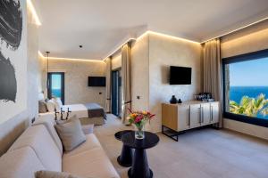 a hotel room with a couch and a bed and a television at Tropicana Hotel , Suites & Villas Mykonos in Paradise Beach