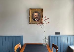 een eettafel met een foto van een man aan de muur bij Appartement Zonderland in Wapenveld