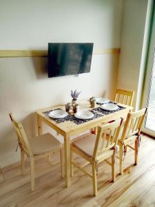 a dining room table with four chairs and a television at Apartament Janka in Zator