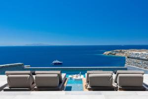 a pool with chaise lounge chairs and the ocean at Tropicana Hotel , Suites & Villas Mykonos in Paradise Beach