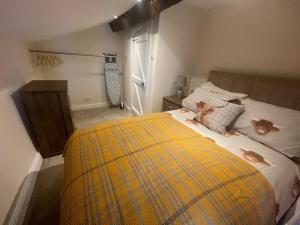 1 dormitorio con 1 cama con manta amarilla en Whitebrook Cottage, en Mellor