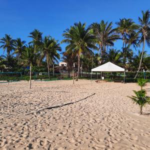 a sandy beach with a white umbrella and palm trees at Bangalô 12 na praia de Guaratiba, Prado, ba in Prado