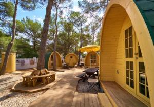 eine Holzterrasse mit einem Picknicktisch und einem Gebäude in der Unterkunft Camping Escana in Es Cana