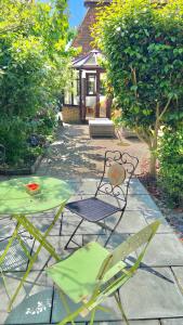 un patio con 2 sillas, una mesa y una casa en Beautiful Bexhill Cottage with garden 3 mins walk to beach en Bexhill