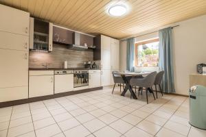 a kitchen with white cabinets and a table with chairs at Haus Bärbel in Geisfeld
