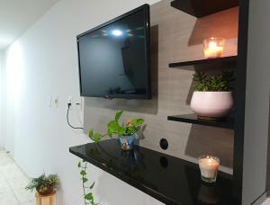 a living room with a tv and a black table at Flat mobiliado praia, João Pessoa PB PROMOÇÃO in Cabedelo