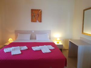 a bedroom with a red bed with two white towels on it at Cavo Plako Villas in Palekastron