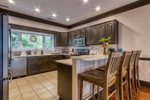 a kitchen with wooden cabinets and a bar with chairs at The Great Escape chalet in Sevierville