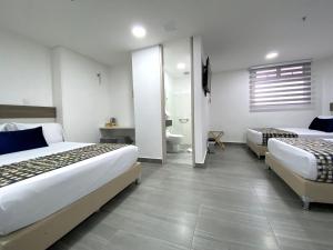 a hotel room with two beds and a bathroom at Seven Inn Hotel in Medellín