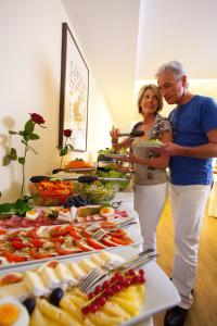 a man and woman standing in front of a buffet of food at Kurhotel Panland in Bad Füssing