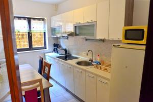 a kitchen with white cabinets and a sink and a microwave at Apartments Opatija Sea View in Opatija